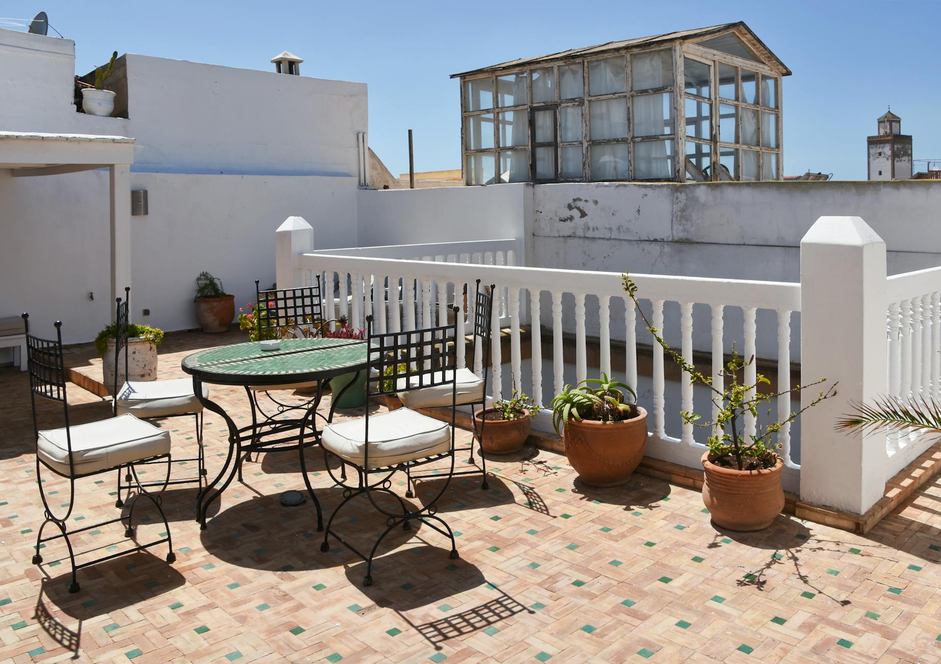 Słoneczny taras na dachu z płytkami gresowymi, krzesłami i roślinami