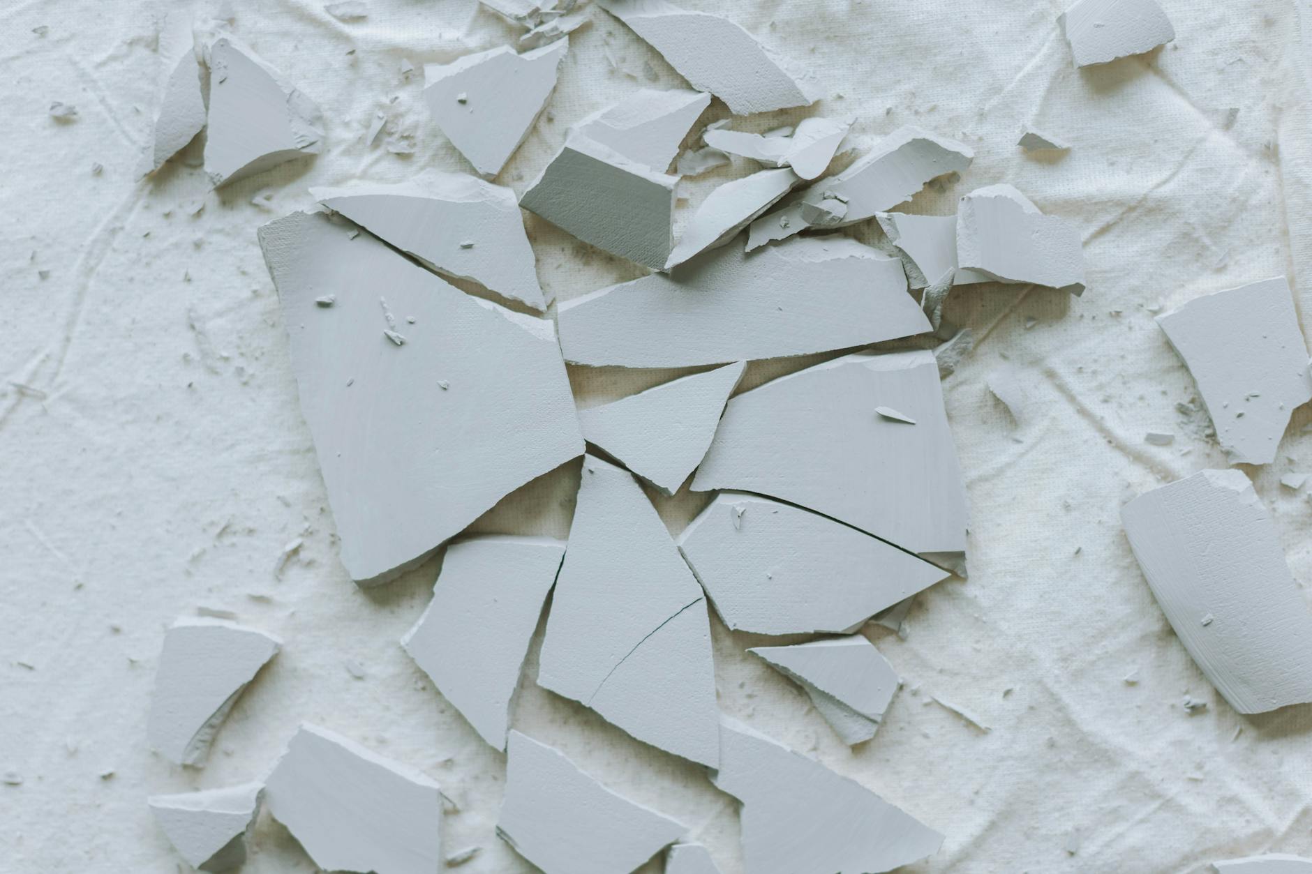 Potłuczone płytki ceramiczne rozrzucone na białym podłożu