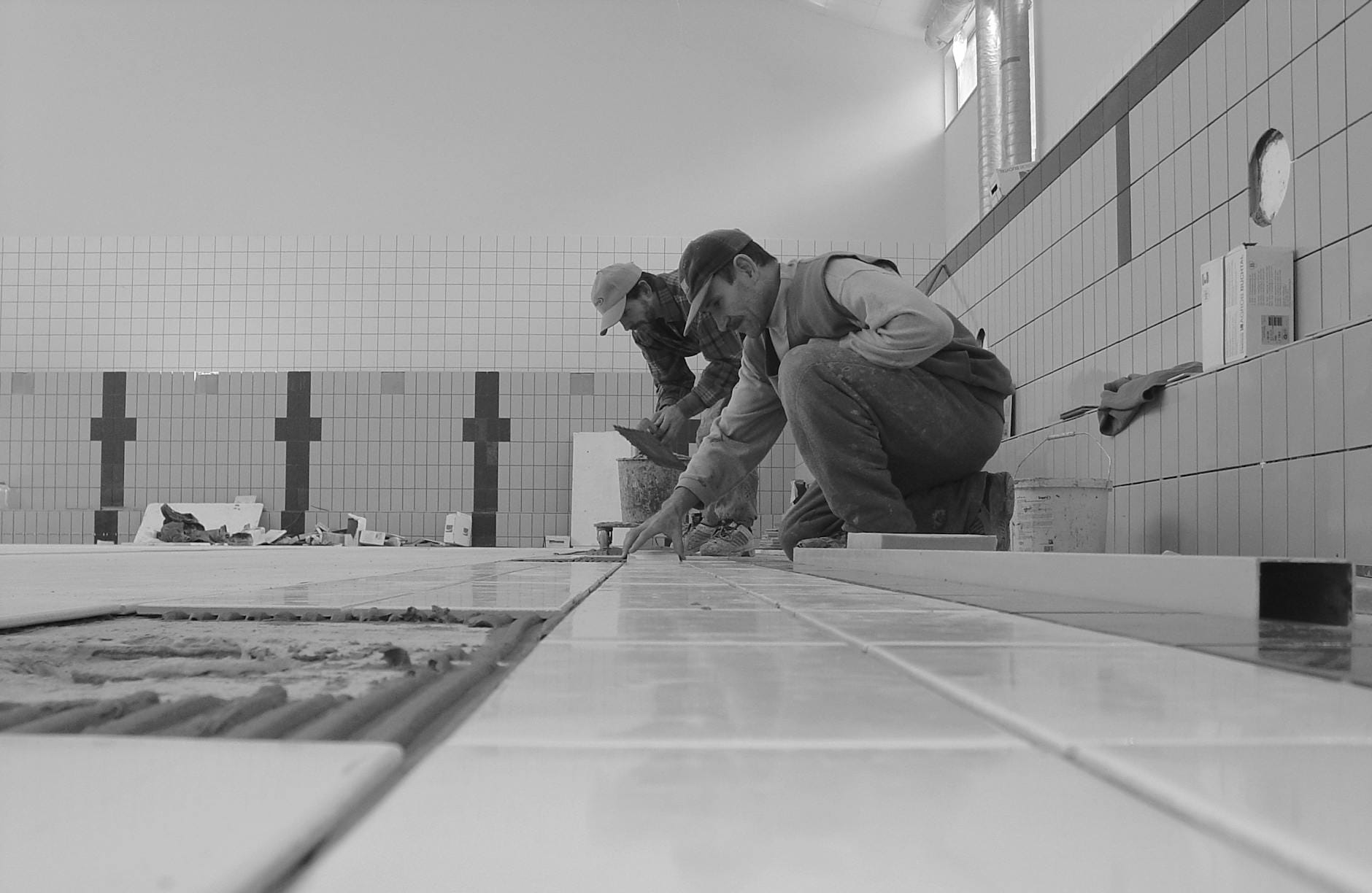 Pracownicy układają płytki w łazience podczas prac wykończeniowych