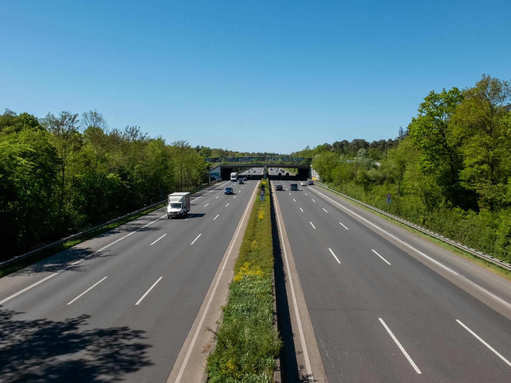 Pusta autostrada w słoneczny dzień otoczona zielenią