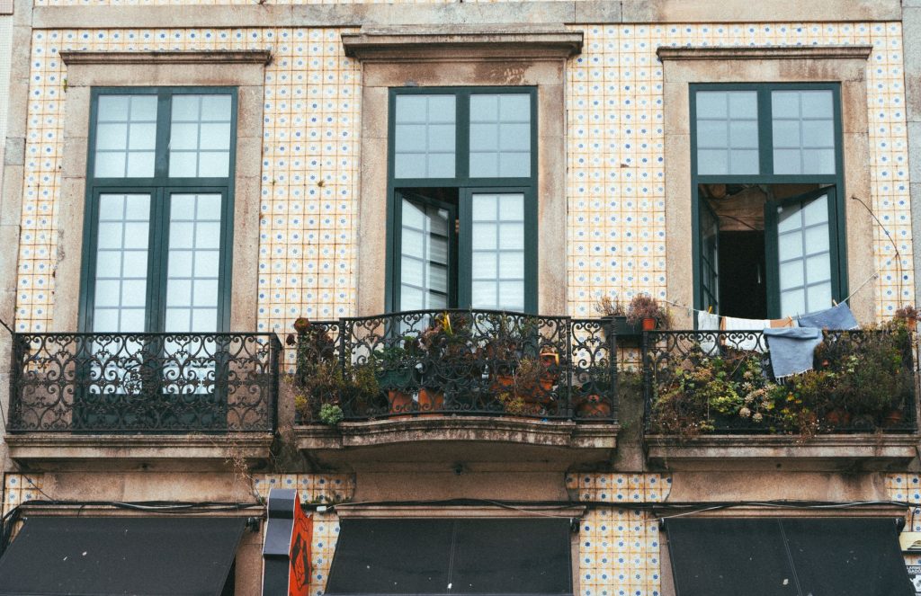 Ozdobny żelazny balkon na tle kafelkowej elewacji w Porto